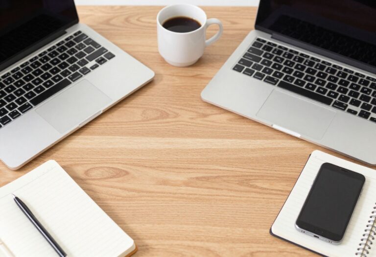 Flat lay of laptop, coffee, notebook, and smartphone on a wooden desk